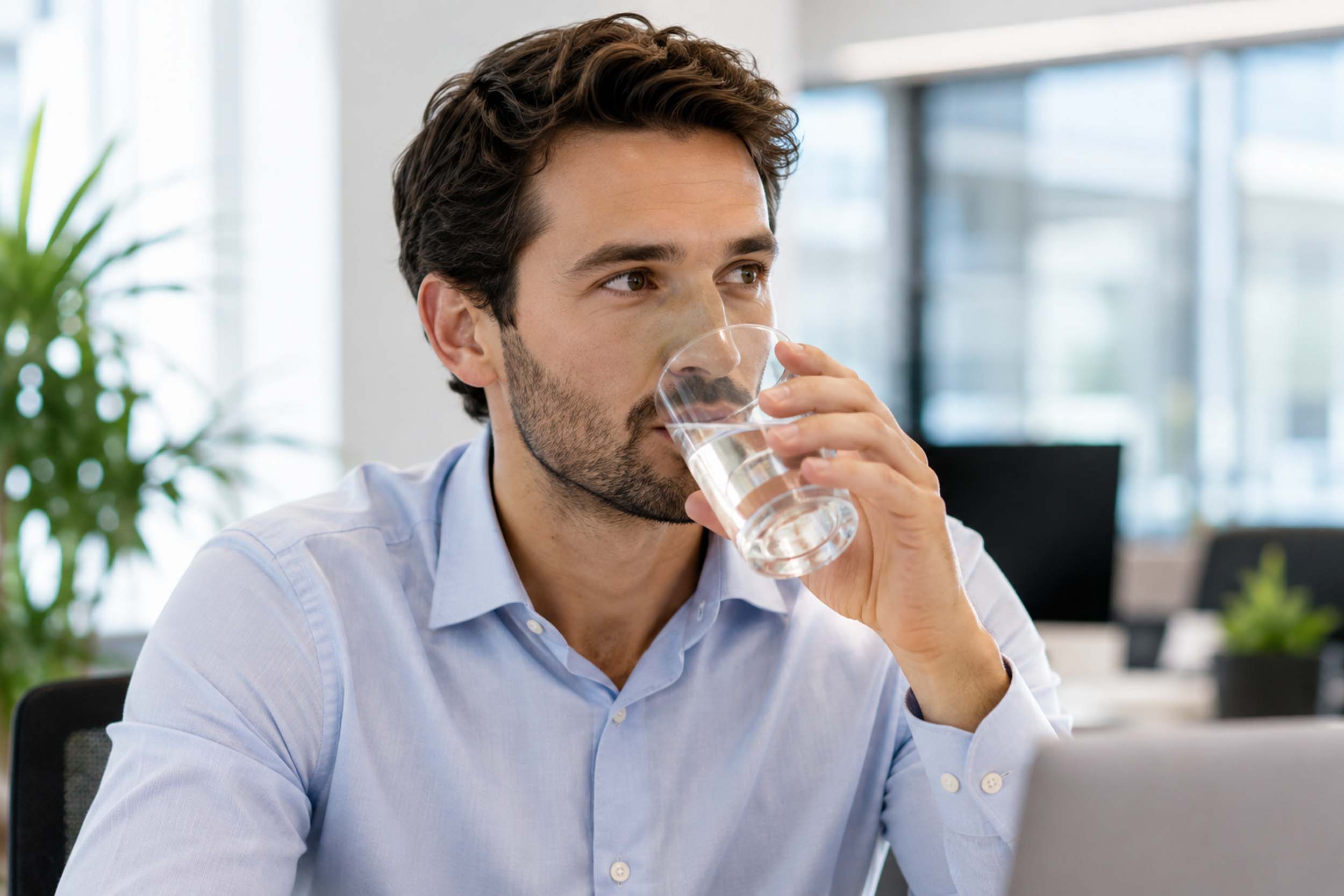 Impiegato che beve acqua in ufficio